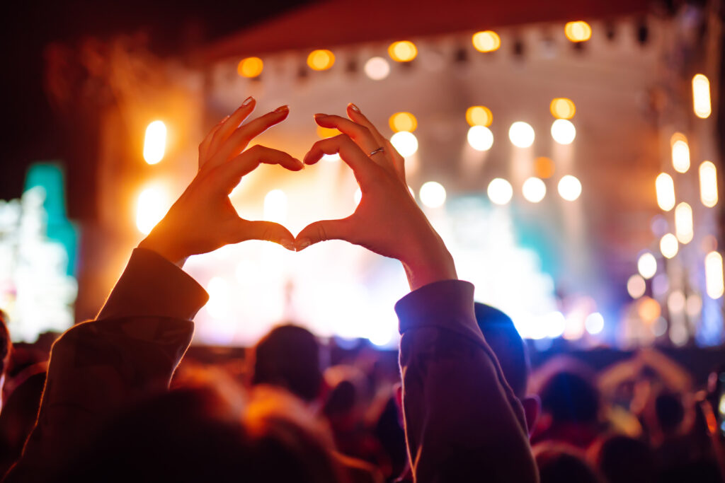 Heart shaped hands concert, loving artist, festival. Music concert with lights, silhouette of people
