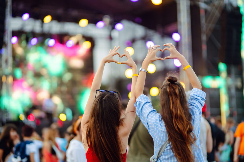 Heart shaped hands at concert. Music concert with lights and silhouette of people enjoying concert.